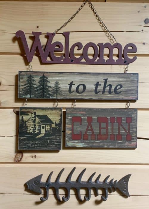 Hanging sign against a light wooden wall that says 'Welcome to the Cabin'