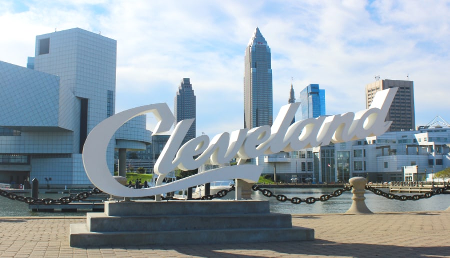 Fun things to do in Cleveland involve finding the large white Cleveland script sign in front of downtown high rise buildings